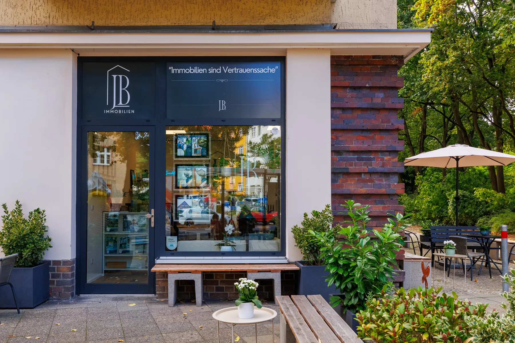 Eingang des Büros von JB Immobilien in der Albrechtstraße 48, Berlin-Steglitz: Schaufenster mit Logo und dem Leitsatz „Immobilien sind Vertrauenssache“